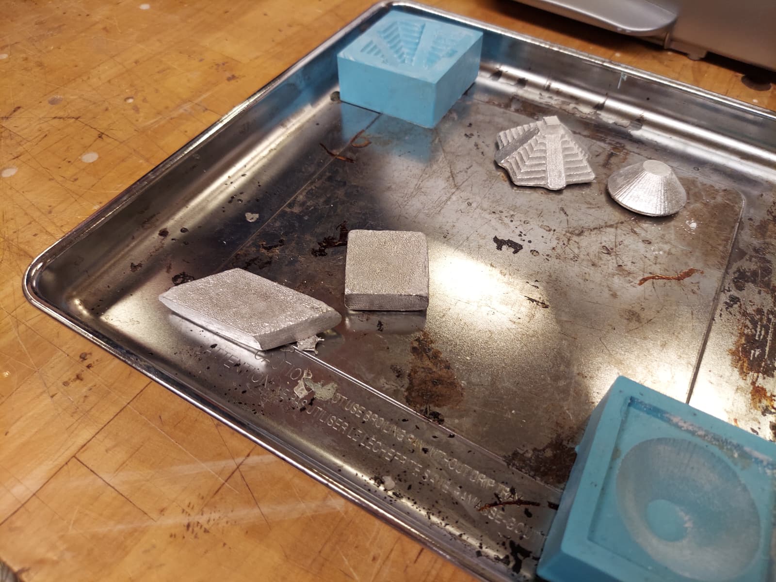 Metal cast shapes on tray next to silicone molds
